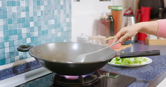 close up hand asian woman is using wok to cook with much oil smoke in kitchen - one of the causes for lung cancer