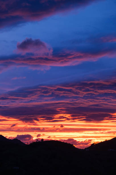 istock The sun setting behind a backdrop of clouds and towering mountains, casting a warm glow over the landscape. 2148416900
