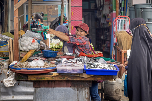 Berastagi, North Sumatra, Indonesia - January 26th 2024:  Female fishmonger at work in her market stall at an outdoor street market
