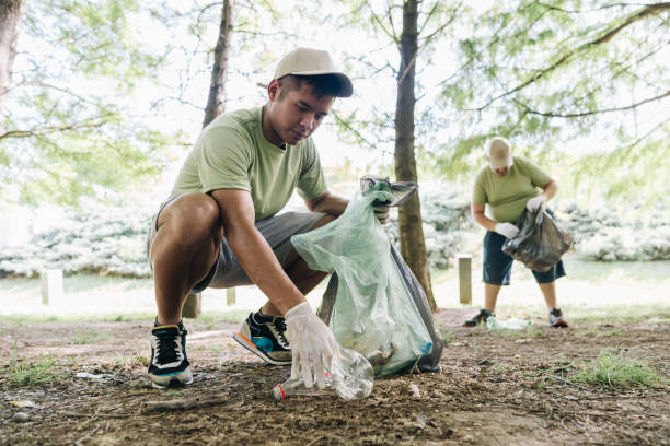 Young man volunteer collecting trash in public park