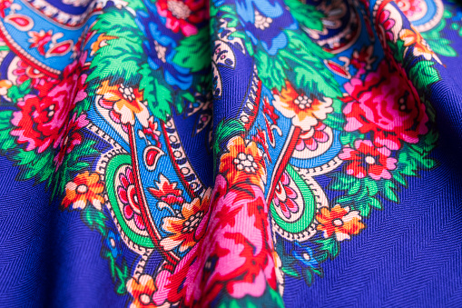 Beautiful blue cotton Russian shawl with vivid floral design, traditional winter scarf background.