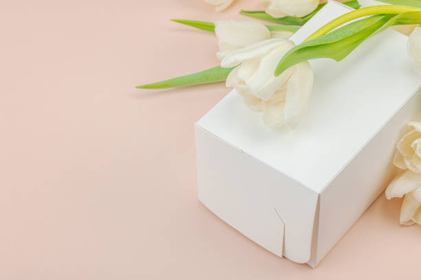 istock Gift concept. Wrapped surprise box, white tulips on apricot background 2148418998