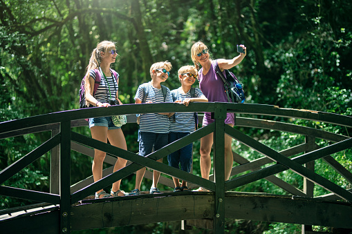 Family is hiking in the mountains of Calabria, Italy on a summer day. Family is standing on a bridge over a mountain stream.\nSunny summer vacations day.\nShot with Canon R5