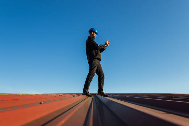 istock Young man worker in helmet standing on roof using mobile phone with blue sky. Roofer work background 2148421279