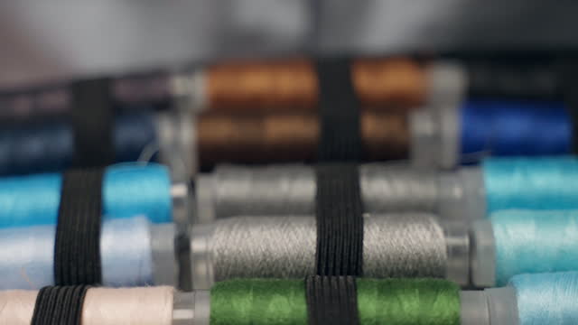 Close-up shot of multicolored thread spools for sewing or repairing clothing, high quality cotton thread reels used in tailor's workshop, necessary tools for dressmaker small business