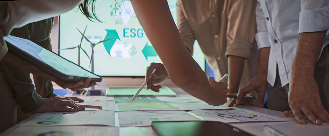 Group of businesspeople in team brainstorm meeting discussion on ESG (Environmental, social, corporate governance) organization planning. Sustainable business practice, people work at night. Close up