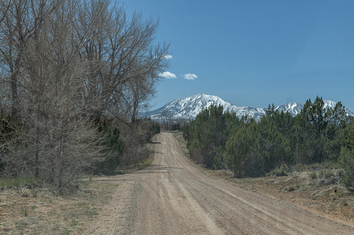Dirt road near Spanish Peaks with reflection in southwestern Huerfano county of Colorado in western USA of North America. Elevation is about 13631 feet high. formed by ancient volcanic activity and erosion. Nearby towns are Pueblo, Denver, Colorado Springs, Trinidad, and Walsenburg, Colorado. Photo from Lathrop State Park.