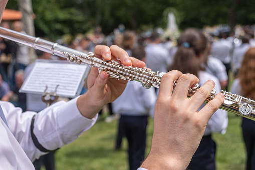close-up view of a musician's hands playing a flute at an outdoor concert