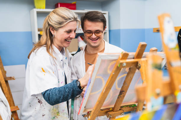 istock Art Teacher Assisting a Student with Down Syndrome in Painting 2148429304