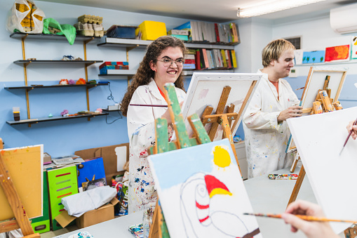 Smiling young artist with glasses creating a vibrant artwork in class.