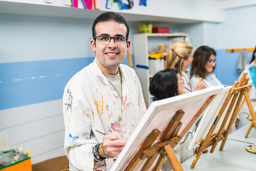 Concentrated man with glasses painting in a disability-friendly art class.\