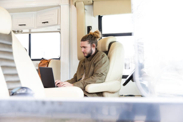 istock At stop in road trip, hipster uses laptop for work 2148430141