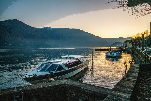 Small passenger boat moving to Como town on Lake Como - zigzag moving  .  Small speed motorboat anchored near coast on  Como lake   sunset and darkis coming