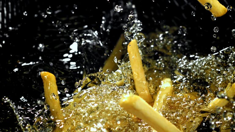 Super slow motion French fries are deep-fried in oil