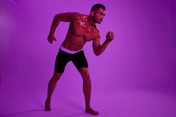 istock Man athletic bodybuilder poses with nude torso abs in full-length background, boxing and martial arts. Advertising, sports, active lifestyle, color light, competition, challenge concept. 2148432949