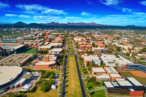 Aerial of the University of Arizona in Tucson, with the Downtown Tucson skyline and the Tucson Mountains in the background.