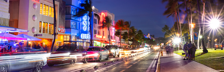 Miami, Florida - April 5, 2023:  People walk along Ocean Drive by the outdoor restaurants, bars, boutiques and luxury hotels in the Art Deco district in South Beach Miami at night
