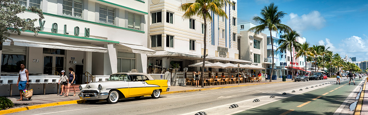 Miami, Florida - April 3, 2023:  People walk along Ocean Drive by the outdoor restaurants, bars, boutiques and luxury hotels in the Art Deco district in South Beach Miami.