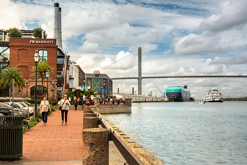 Savannah, Georgia, USA – October 31, 2022:  People walk along the historic waterfront of converted cotton warehouses in downtown Savannah by the Plant Riverside District on the Savannah River