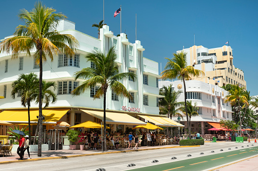 Miami, Florida - April 4, 2023:  People walk along Ocean Drive by the outdoor restaurants, bars, boutiques and luxury hotels in the Art Deco district in South Beach Miami.