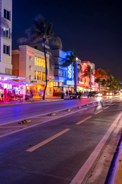 Miami, Florida - April 5, 2023:  People walk along Ocean Drive by the outdoor restaurants, bars, boutiques and luxury hotels in the Art Deco district in South Beach Miami at night