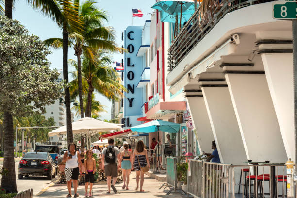 Miami, Florida - April 4, 2023:  People walk along Ocean Drive by the outdoor restaurants, bars, boutiques and luxury hotels in the Art Deco district in South Beach Miami.