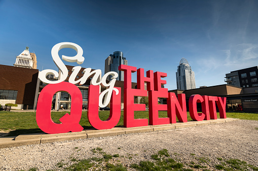 Cincinnati, Ohio - April 10, 2023:  Cincinnati Ohio downtown city skyline and the Sing the Queen City tourist sign by the banks of the Ohio River.
