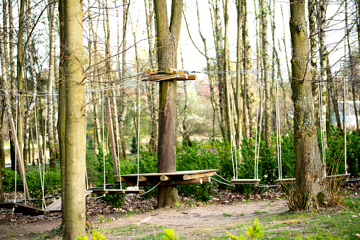 Outdoor activity with fun. Sport in the forest. A rope park is a rope structure mounted on trees or poles, used for safe fun at heights. This is the safest way to practice physical recreation similar to mountaineering. Rope parks provide unforgettable experiences, adrenaline and exercise in the fresh air. It is fun for children, teenagers, adults and older people.\nVarious obstacles made of wood, steel ropes, plastic ropes or mesh are hung between the trees (or poles). The most common ones include hanging footbridges, beams suspended on cables, U-shaped cables, zip lines, net walks, and rope jumps.