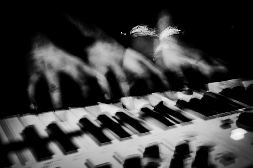 A photo of a musician's hands moving across the keyboard shot using a slow shutter speed to achieve the ghostly effect.