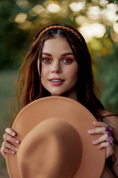 Young hippie woman holding a hat and smiling sincerely while looking at the camera in nature in the fall. High quality photo