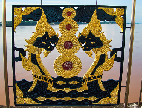 Nong Khai, Thailand, July 19, 2022. Decoration of black and gold nagas (mythical serpents) on the metal fence along the Mekong riverside promenade in Nong Khai, Thailand