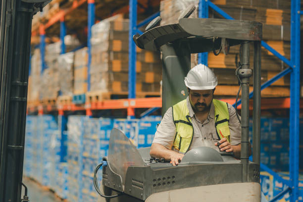 istock Man worker at forklift driver happy working in industry factory logistic ship. Man forklift driver in warehouse area. Forklift driver sitting in vehicle in warehouse 2148439130