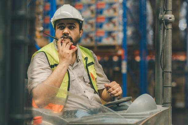 istock Man worker at forklift driver happy working in industry factory logistic ship. Man forklift driver in warehouse area. Forklift driver sitting in vehicle in warehouse 2148439141