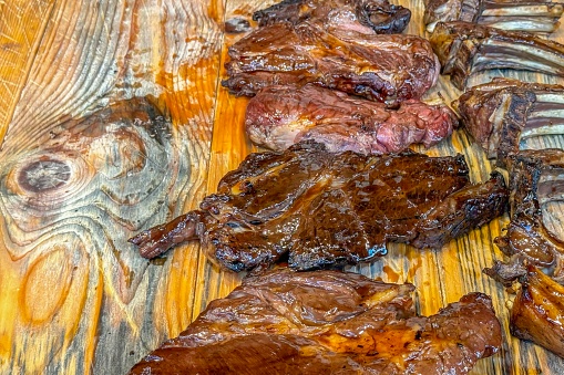 Grilled steaks on a wooden board evoke rustic, outdoor cooking, promise a delicious taste experience, fitting for street food aficionados seeking authentic, hearty flavors