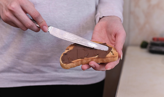 spread a slice of toasted bread with a knife with chocolate butter.