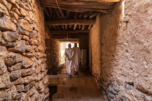 Jebel Akhdar, Oman - 31 October 2023: Two Arab men walking in narrow street in the twin villages of As Shuraija and Al Ain, Oman