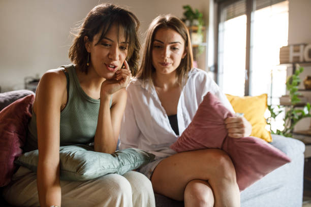 istock Two girlfriends sitting on the sofa, surfing the net via laptop 2148441252