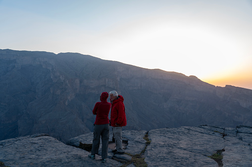 Two people at sunset standing at the edge of Oman - Grand Canyon/Wadi Nakha