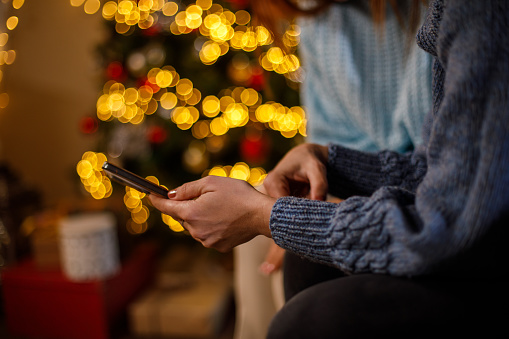 Close-up shot of two mid adult women surfing the internet using mobile phone, spending Christmas holidays together, holding mobile