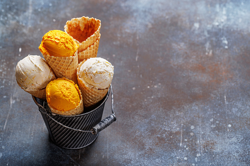 Assorted ice cream flavours in delightful waffle cones, a treat for every taste bud. Over stone background with copy space