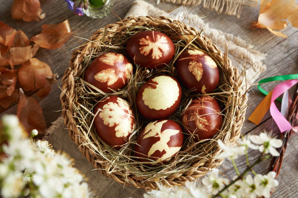 istock Brown Easter eggs dyed with onion peels in a wicker basket with spring flowers 2148442292