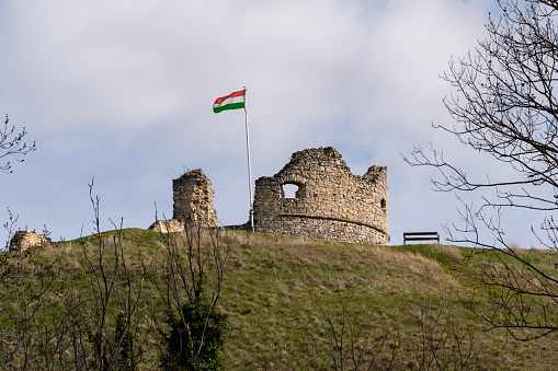 Ruins of a medieval castle with a Hungarian flag near Döbrönte on a sunny day in springtime.