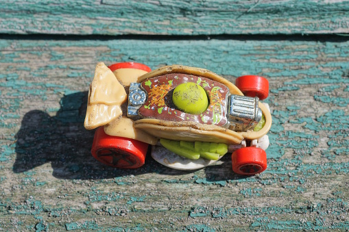 one small colored plastic car stands on a green gray wooden table