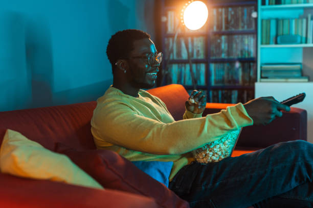 istock Young man relaxing at home and watching TV 2148443055