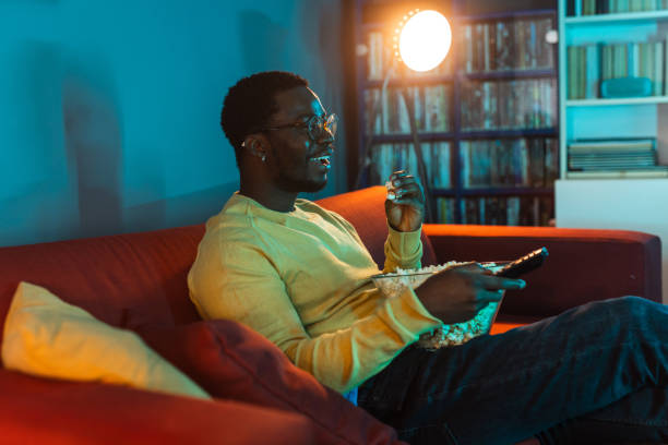 istock Young man relaxing at home and watching TV 2148443056