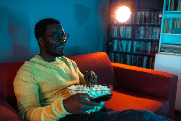 istock Young man relaxing at home and watching TV 2148443081