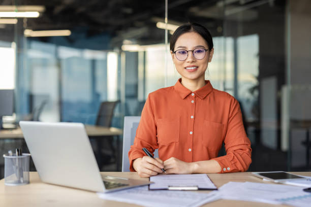 istock Confident businesswoman smiling in office setting with laptop and documents 2148443257