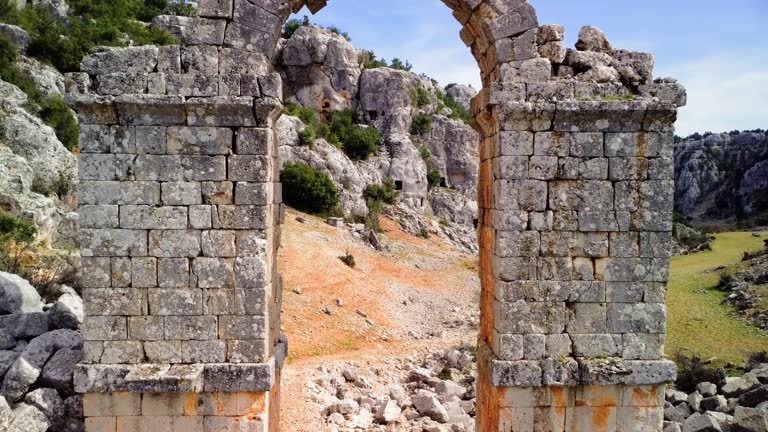 Aerial video of Olba ruins, Turkey, showcasing main ancient city gate. Drone explores gate structure, historic gate amid ruins. View architectural remnants, gate in landscape