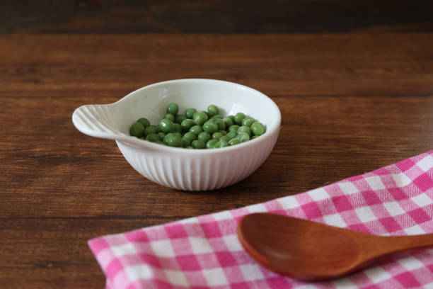 istock Green peas in a bowl on a wooden table. 2148444375