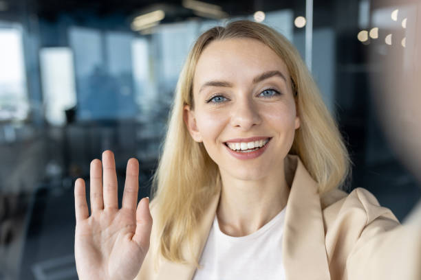 istock Professional woman smiling and waving in a modern office 2148444403